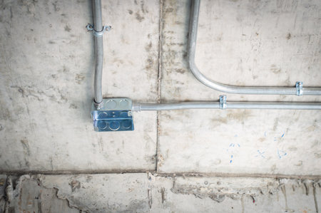Electrical conduit for cable routing between electrical distribution panel with Galvanized electrical junction box and Pipe of electricity line installed in buildings. Selective focus.の写真素材