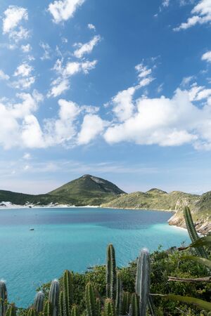 View from the hiking trail at Arraial do Cabo, at the end of the Prainhas do Pontal do Atalaia Beach Small Beaches, overlooking Ilha do Farol. There are cactuses and turquoise water on a sunny day.の写真素材