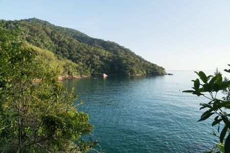 Early morning view at the lookout over Praia de Mangues Beach, Ilha Grande island, state of Rio de Janeiro, Brazil, from the trail to Praia Lopes Mendes. There is green mountains, blue sea and sky.の写真素材