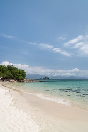 Tropical beach on the island Ilha Cataguas off the coast of Angra dos Reis in the state of Rio de Janeiro, Brazil. There is calm turquoise water, white sand, rocks, trees, blue sky and mountains.の写真素材