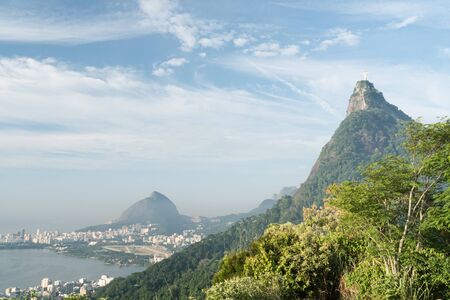 View of Corcovado Mountain and Christ the Redeemer Statue from Mirante Dona Marta. The morning blue sky has clouds, with Morro Dois Irmaos and the lake.の写真素材