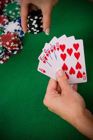 Cards with poker arrangement and female hand betting in the background.