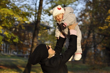 mother with baby is playing and playing in autumn parkの写真素材