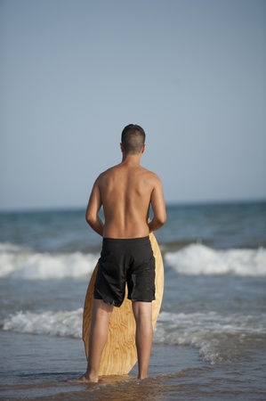 Young man is looking the ocean and waiting to surfの写真素材