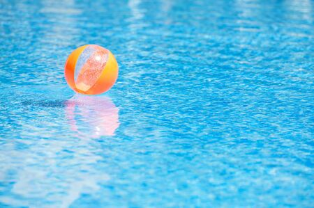 orange ball in the blue water swimming poolの写真素材