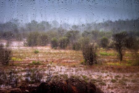 view of the landscape through the glass with raindropsの写真素材