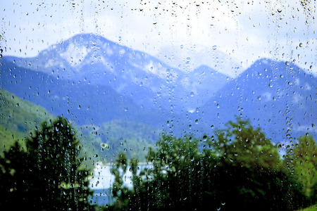 view of the mountains through the glass with raindropsの写真素材