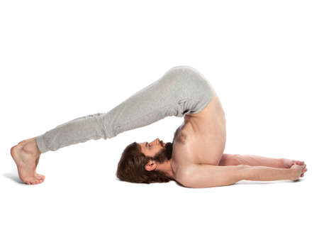 Young man with beard doing yoga on a white background