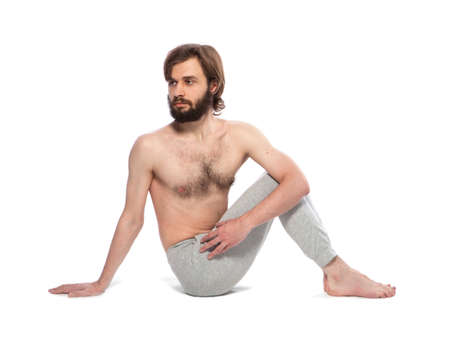 Young man with beard doing yoga on a white background