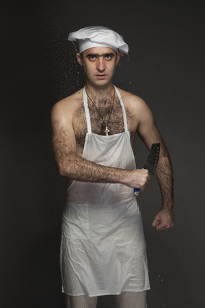 Portrait of a wet cook in an apron with a knife in his handsの写真素材