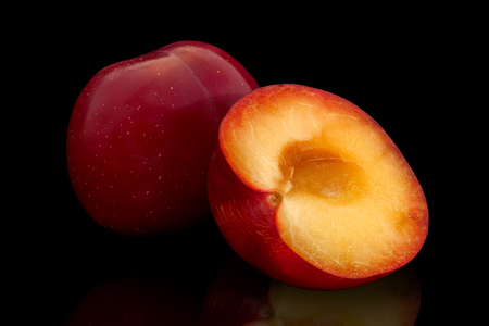 Ripe red plum and half plum on a black backgroundの写真素材