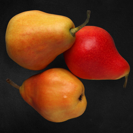 Three ripe pears on a dark stoneの写真素材