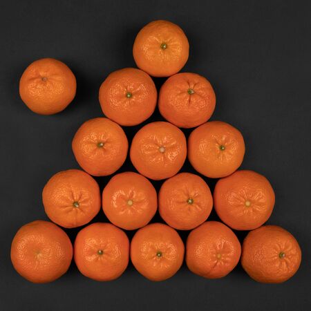 Top view on a billiard pyramid of fifteen tangerines on a gray backgroundの写真素材