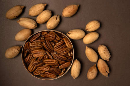 Bunch of pecan not cleared and nuts on brown background. View from above
