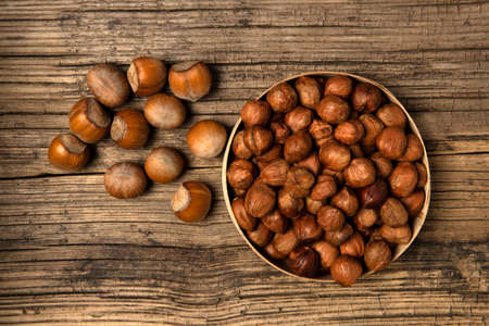 Bunch of hazelnut not purified and purified on old wood background. View from above