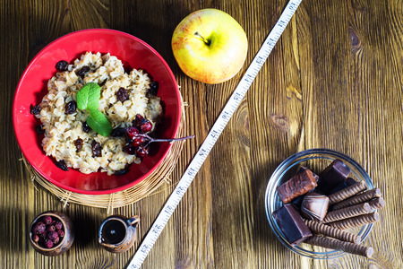 Healthy vs  unhealthy food. Concept of making choice of food: fruit, oatmeal  or candy, separated by a measuring tape. Time for slimming.の写真素材