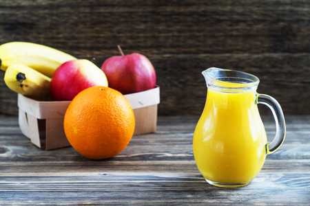 Fresh exotic fruits and juice in glass jug on wooden backgroundの写真素材