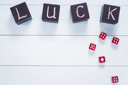 Luck word written in black wooden cubes and red dice on a blue wooden background, flat lay. Concept for business risk, chance, good luck or gambling, top view.の写真素材
