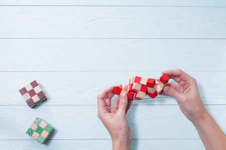 Logic background. The concept of logical thinking. Wooden colorful cubes, puzzle. Hands holding wooden conundrum.の写真素材