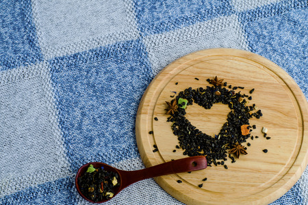 Heart of dried petals of green tea on knitted tablecloth with place for your textの写真素材