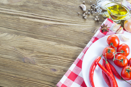Ingredients for tomato sauce, top view. Tomatoes, red hot pepper, oil, spices, salt, onions, garlic on a wooden background with copy space.の写真素材