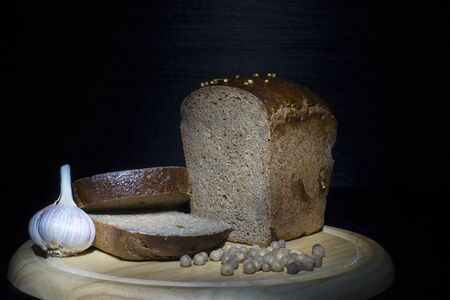 Rural concepts. Dark rye bread, allspice and garlic on black.