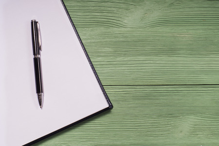 Open blank notebook and pen on a green wooden background, top view. The concept started, flat lay.の写真素材