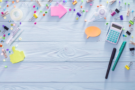 Office, business, education still life concept on blue wooden background. Top view of wooden desktop...