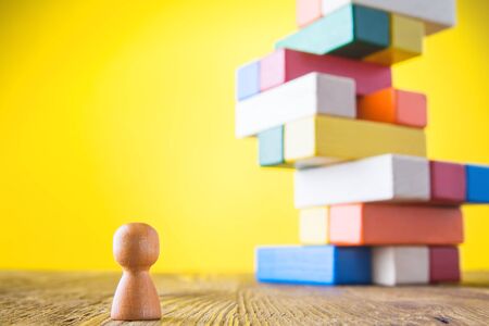 Business metaphor of businessman climbing colorful career stairs on yellow background. Going up concept using stairway of wood blocks. Achieving success. Business competition. Career, social status.の写真素材