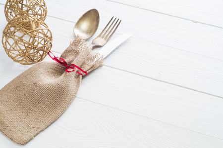Rustic cutlery set: vintage knife, fork and spoon on a white wooden background. Table with antique cutlery on the burlap with copy space, close-up. Cutlery wrapped in burlap.の写真素材