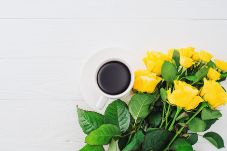 Cup of coffee with bouquet of yellow roses, flat lay, top view. Greeting card template. Floral background for mother's day, wedding invitation, greetings and invitation card.の写真素材