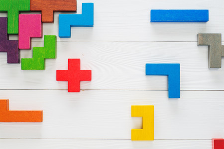 Concept of creative, logical thinking. Different colorful shapes wooden blocks on white wooden background, flat lay, copy space. Geometric shapes in different colors, top view. Abstract Background.の写真素材