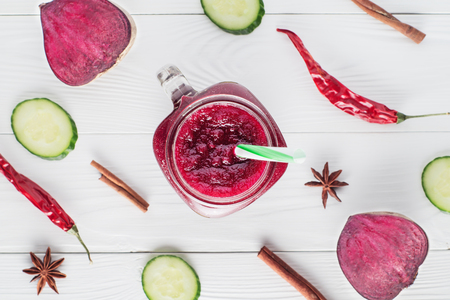Beetroot smoothie in a mason jar with a straw and ingredients on a wooden background. Fresh beet juice, detox, top view, flat lay. Organic antioxidant smoothies made of beet, apple, cucumber. Healthy vegan raw food.の写真素材