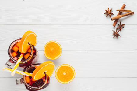 Two fruit tea in vintage glass jars with drinking straw on white wooden  background top view. Vintage mason jars with ice red tea, orange, cinnamon and star anise on white table, flat lay.
の写真素材