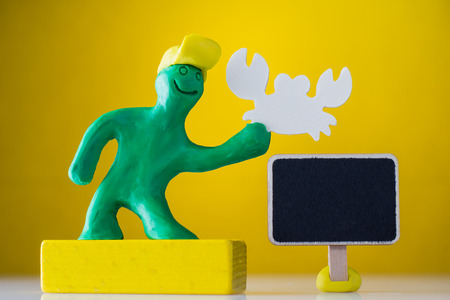 Plasticine man holds a crab. Empty wooden tablet for text.の写真素材