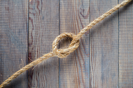 Knot of the rope on the wooden background.  Rope with knot on blank antique brown rustic wood background with copy space.の写真素材