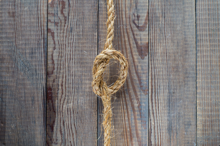 Knot of the rope on the wooden background.  Rope with knot on blank antique brown rustic wood background with copy space.の写真素材
