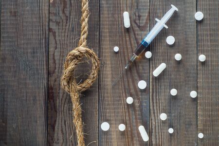 Concept Stop drugs: a syringe, pills and a rope with a knot on a wooden background. No drugs or anti doping in sport or zero tolerance to drugs. Drugs, pills, top view, flat lay.の写真素材