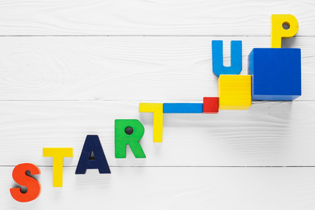 Startup word made from colored wooden letters on an white table. Startup business concept. Abstract colorful cube shapes and word startup on white background.の写真素材