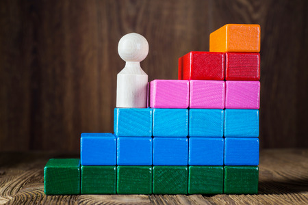 Business metaphor of businessman climbing colorful career stairs on wooden background. The concept of career, social status. Achieving success. Business competition.の写真素材