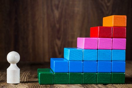 Business metaphor of businessman climbing colorful career stairs on wooden background. The concept of career, social status. Achieving success. Business competition.の写真素材