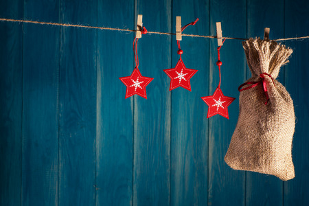 Christmas background. Christmas bag present and red stars on clothespin on deep blue wooden background with copy space. Christmas or New Year card template.の写真素材