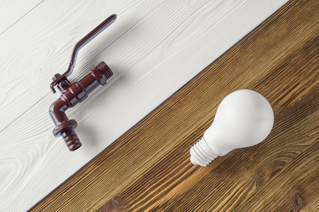 Brown tap and light bulb on wooden background. Two energy, water and electricity. Eco concept.の写真素材