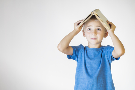 Portrait of little smiling schoolboy with book. Cheerful smiling little kid. School concept.の写真素材