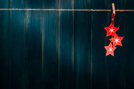 Blue Christmas background with wooden red stars, christmas toys hanging on clothespin on grunge wooden wall. Xmas and New Year concept.  Christmas or New Year card template with copy space.の写真素材