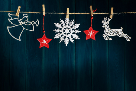 Christmas angel with wings and trumpet, reindeer, red christmas stars and snowflakes on clothespin on deep blue wooden background with copy space. Layout greeting card for winter holidays.の写真素材
