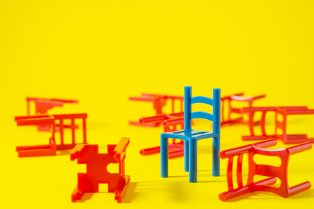 Unique red chair in a group blue others. Leadership concept. Empty chairs  on yellow background. The concept of uniqueness, distinction from others.の写真素材