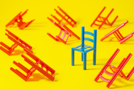 Unique red chair in a group blue others. Leadership concept. Empty chairs  on yellow background. The concept of uniqueness, distinction from others.の写真素材