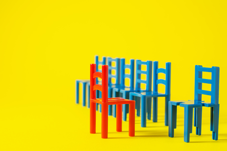Unique red chair in a group blue others. Leadership concept. Empty chairs  on yellow background. The concept of uniqueness, distinction from others.の写真素材