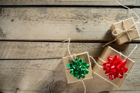 Three craft cardboard  gift boxes on a rustic wooden background. Gift kraft boxes with ribbon bow and rope.の写真素材